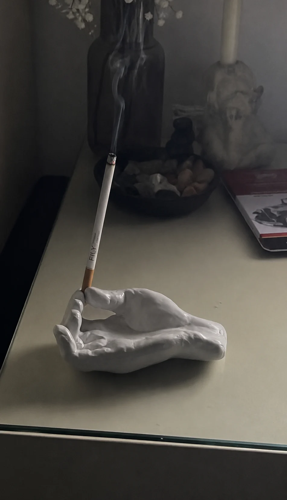Incienso FILY apoyado en un soporte con forma de mano, en una mesa de noche con luz tenue
